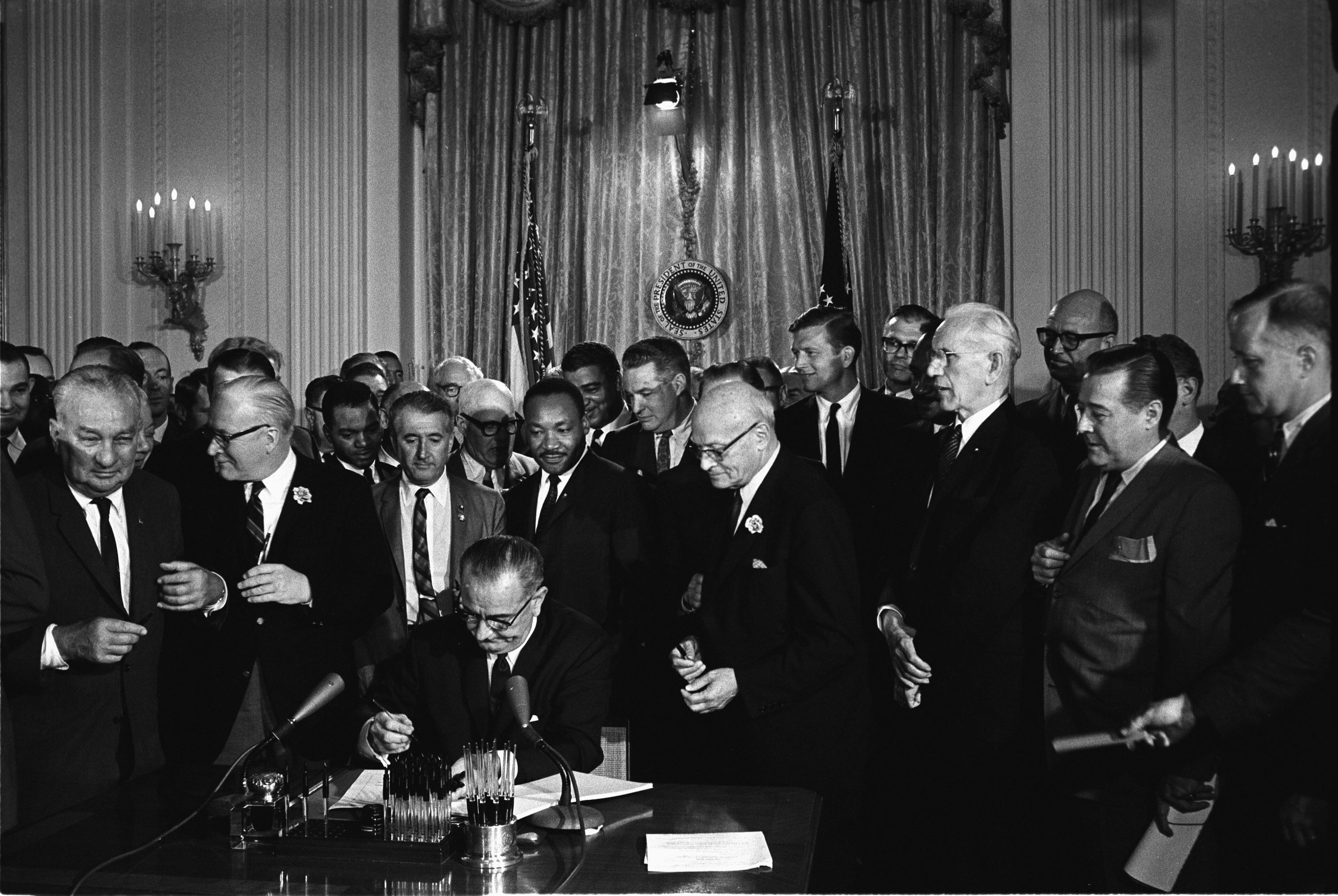 President Lyndon B. Johnson signing the Civil Rights Act on 2 July 1964, surrounded by officials